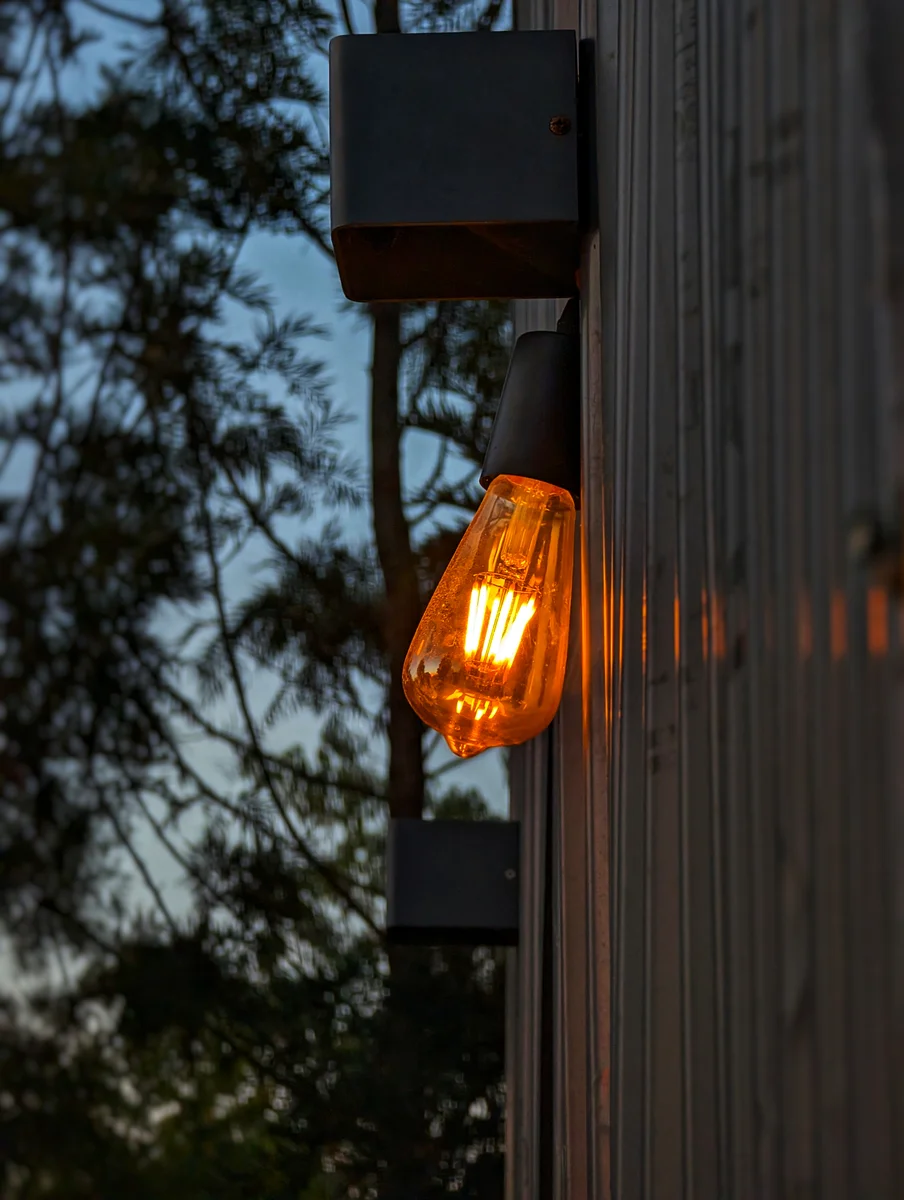 A warm hanging bulb outside a timber cabin