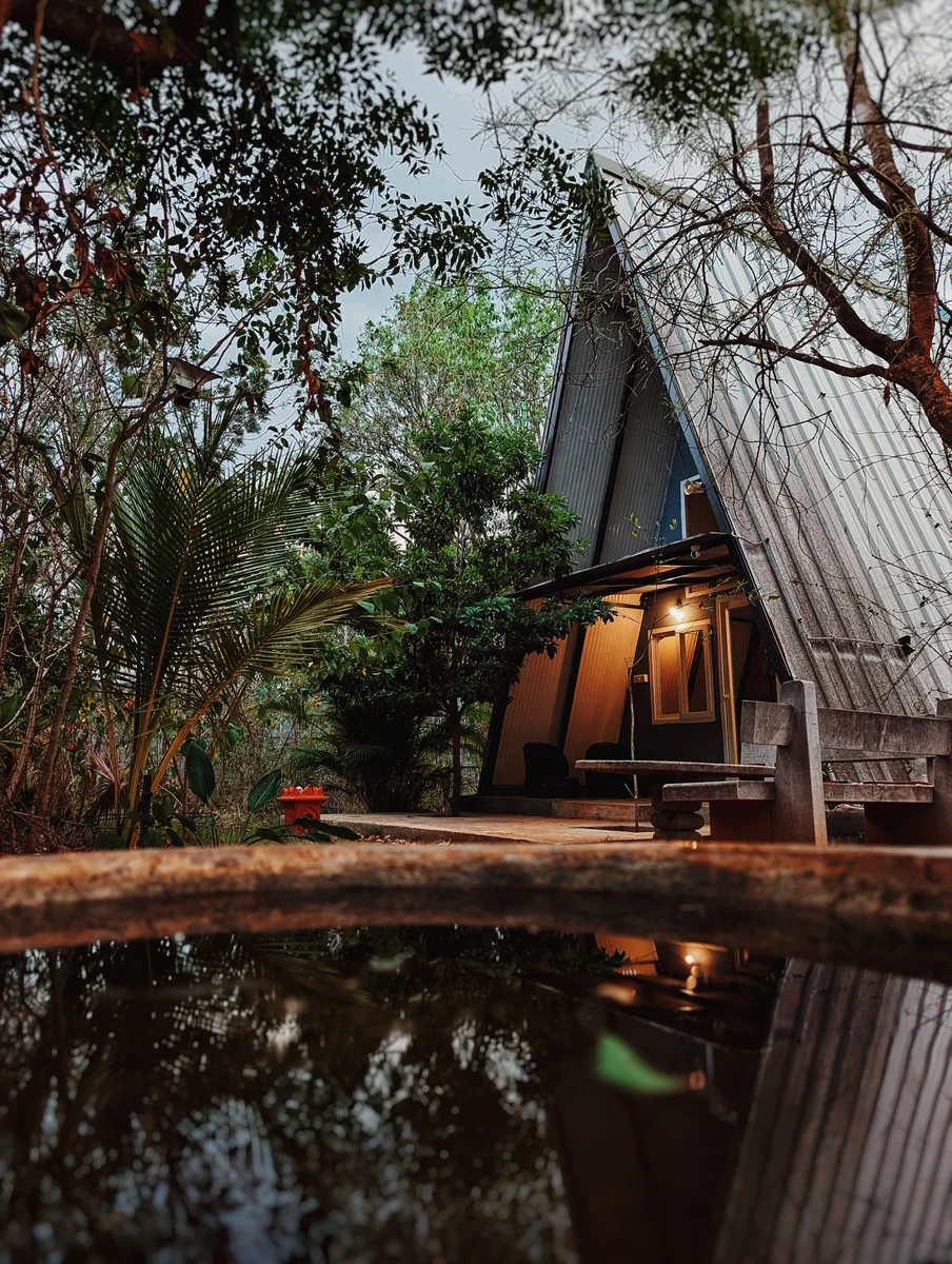 An A-frame cabin reflected in still water among trees